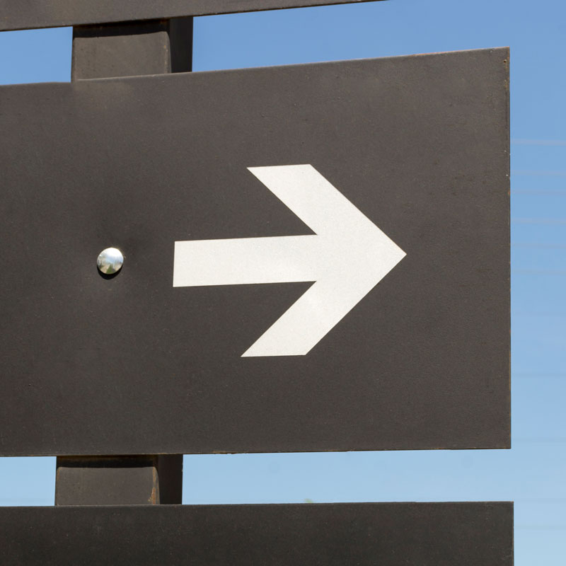 Ein schwarzes Schild, mit einem weißen Pfeil der nach rechts zeigt.