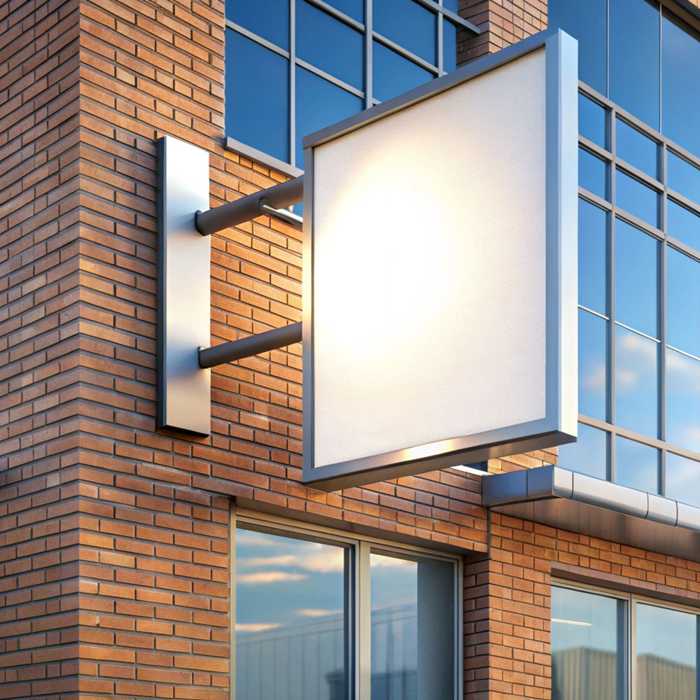 Ein weißes, blanko Nasenschild aus Metall befestigt an einem Gebäude mit roten Backsteinen und großen Glasfronten